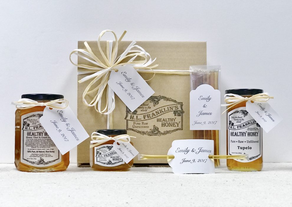 A rustic gift box with honey jars, candle, and soap, decorated with twine and tags.